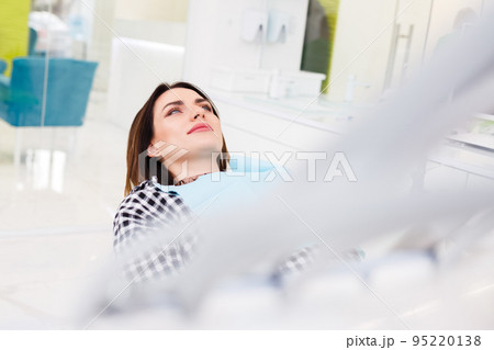 Female patient lies in the dental chair waiting for the treatment process. 95220138