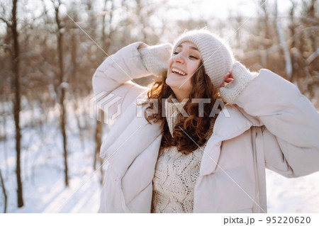 Young woman in winter style clothes walking in the snowy park. Winter fashion, holidays. 95220620