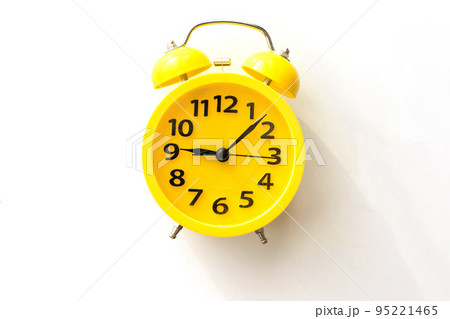 A yellow alarm clock lies on a white table, top view A yellow alarm clock lies on a white table, top view 95221465