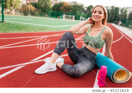 Beautiful slim girl sits on the running surface of the stadium Beautiful slim girl sits on the running surface of the stadium 95221629