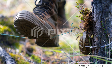 Soldier steps on a mine trap. The soldier's boot rips off the wire and rips off the pin of the grenade. Soldier steps on a mine trap. The soldier's boot rips off the wire and rips off the pin of the grenade. 95221996