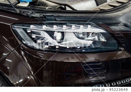 Car headlights and open hood in auto service garage 95223649
