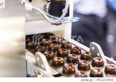 sweets production and industry concept - chocolate candies processing on conveyor at confectionery shop. High quality photo 95223948