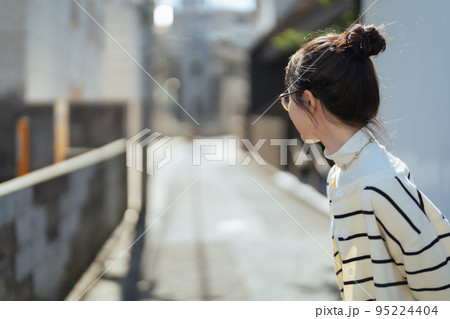 道の先を見る女性 95224404