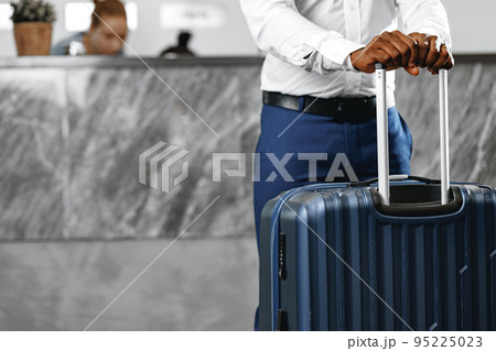 Unrecognizable businessman standing with luggage suitcase in hotel lobby 95225023