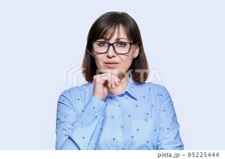 Portrait of serious middle-aged woman on light studio background Portrait of serious middle-aged woman on light studio background 95225444