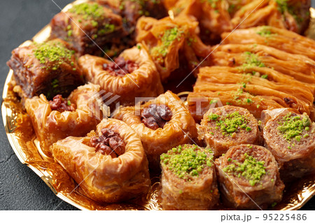 Delicious baklava dessert in oriental setting on black background Delicious baklava dessert in oriental setting on black background 95225486
