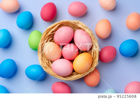 Colorful Easter eggs in decorative nest on blue background Colorful Easter eggs in decorative nest on blue background 95225608