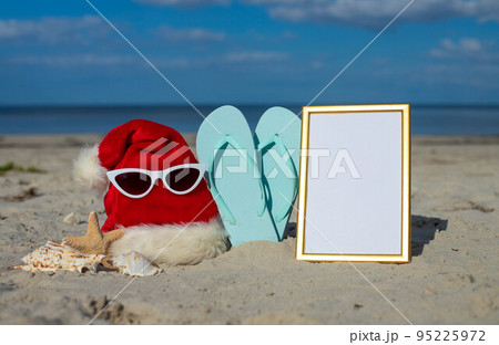 Christmas background Santa Claus hat on the beach with starfish and beach slippers 95225972