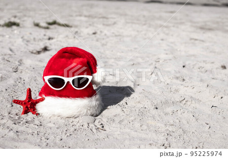 Christmas background Santa Claus hat on the beach with starfish and sunglases Christmas background Santa Claus hat on the beach with starfish and sunglases 95225974