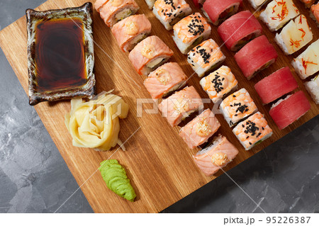 Assortment of different kinds of sushi rolls placed on black stone board. Sushi set with salmon, cucumbers, cream cheese, avocado and sesame seeds. Sushi image for menu 95226387