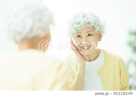 鏡を見てスキンケアをするシニアの女性 95228249
