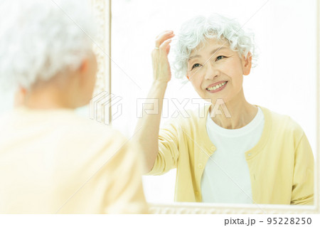 鏡を見てヘアセットをするシニアの女性 鏡を見てヘアセットをするシニアの女性 95228250