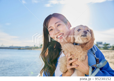 犬と海辺で遊ぶ女性 95230152