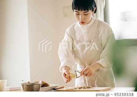 キッチンでじゃがいもの皮を剥く女性 キッチンでじゃがいもの皮を剥く女性 95230338