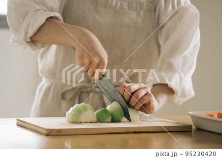 キッチンで玉ねぎを切る女性 キッチンで玉ねぎを切る女性 95230420