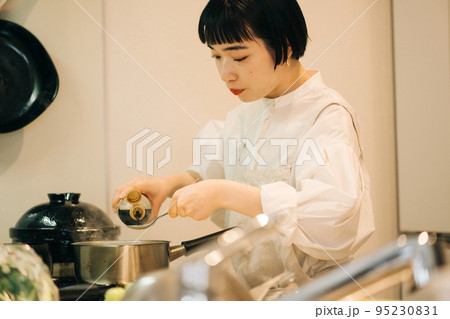 鍋に醤油を入れる女性 95230831