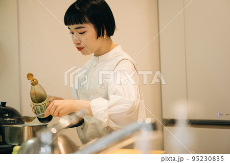 鍋に醤油を入れる女性 95230835