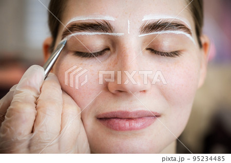 The master draws the shape of the eyebrows with white paint before coloring.  95234485