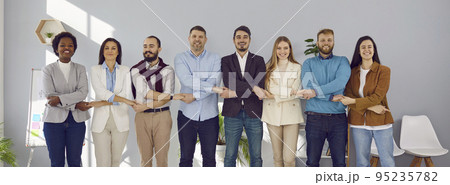 Successful and friendly group of business colleagues standing together in row and holding hands. 95235782