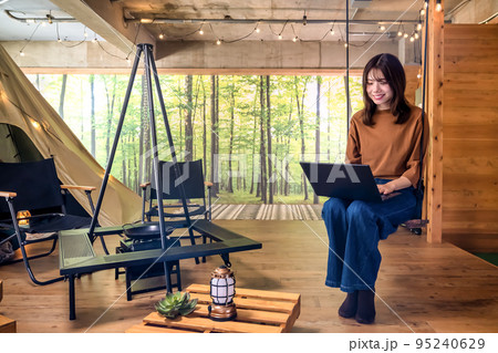 ワーケーション ブランコに座ってノートパソコンを操作する若い女性 ワーケーション ブランコに座ってノートパソコンを操作する若い女性 95240629