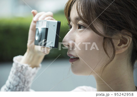 フィルムカメラで街並みを撮影する若い女性 95242958