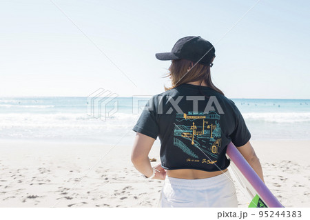 サーフボードを持って海を眺めるの若い女性 95244383