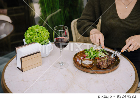Girl cuts a fried steak in a restaurant on the terrace 95244532