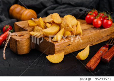Roasted potato wedges on wooden board Roasted potato wedges on wooden board 95244571
