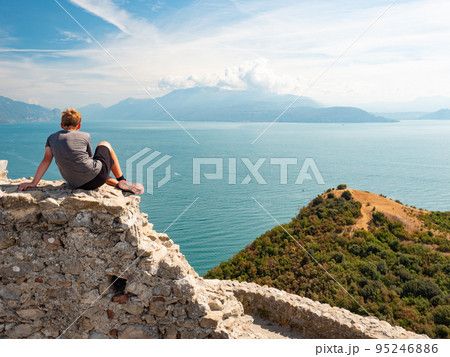 Tired blond hair boy it on the stony wall of ruin Rocca di Manerba Tired blond hair boy it on the stony wall of ruin Rocca di Manerba 95246886