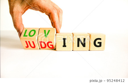 Loving or judging symbol. Concept words Loving or Judging on wooden cubes. Businessman hand. Beautiful white table white background. Business loving or judging concept. Copy space. 95248412