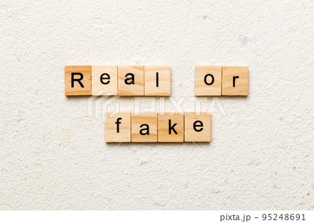 Real or fake word written on wood block. Real or fake text on cement table for your desing, Top view concept 95248691