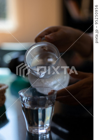 ピッチャーからグラスに水を注ぎ入れているところ ピッチャーからグラスに水を注ぎ入れているところ 95250956