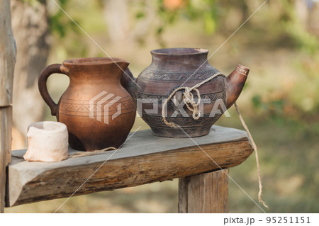 Antique pottery on a wooden surface outdoor in summer, selective focus. 95251151