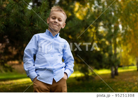 portrait of a cheerful boy in a blue shirt standing with his hands in his pockets against the portrait of a cheerful boy in a blue shirt standing with his hands in his pockets against the 95251308