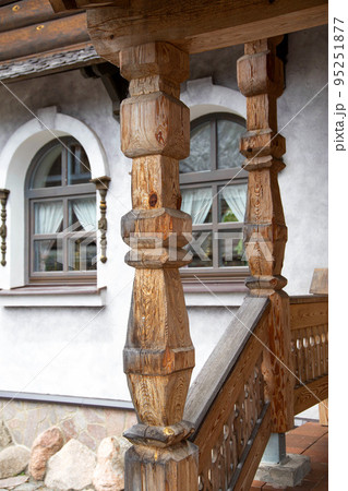 Beautiful carved wooden columns on the porch of a country house, close-up 95251877