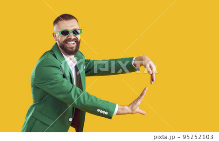 Happy funny man in green suit and sunglasses dancing at St Patrick's Day holiday party 95252103