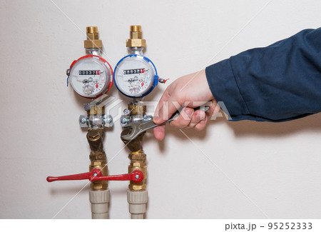 an employee removes water meters to check and replace new ones. Maintenance and repair of water meters an employee removes water meters to check and replace new ones. Maintenance and repair of water meters 95252333