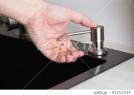 Dispenser for soap and hand hygiene. Modern dispenser built into the kitchen sink, close-up Dispenser for soap and hand hygiene. Modern dispenser built into the kitchen sink, close-up 95252334