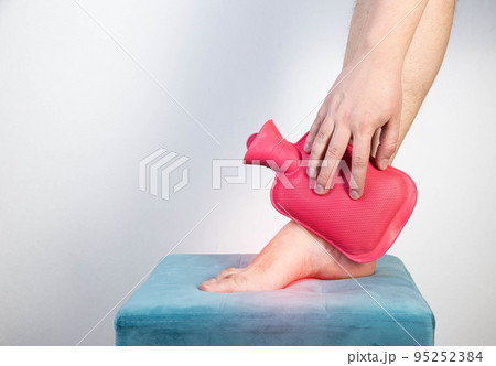 Treatment of arthritis of the ankle joint with a heating pad with hot water. Copy space for text Treatment of arthritis of the ankle joint with a heating pad with hot water. Copy space for text 95252384