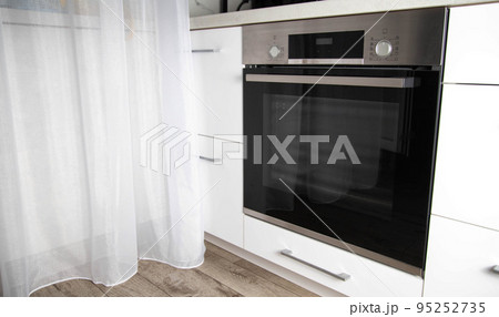 Black modern electric oven built into a white kitchen. Multifunction oven with grill 95252735