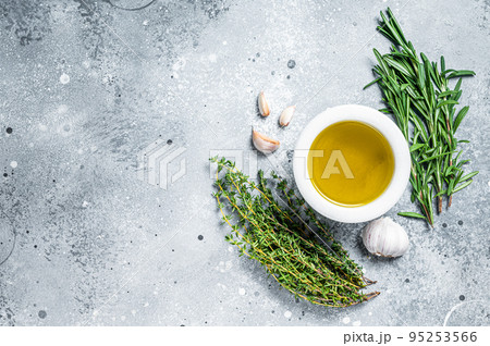 Olive oil with fresh herbs on kitchen table. Top view. Copy space. Gray background Olive oil with fresh herbs on kitchen table. Top view. Copy space. Gray background 95253566