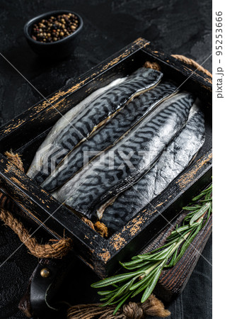 Ready for cooking sliced raw mackerel fillet fish in a wooden box with herbs. Black background. Top view 95253666