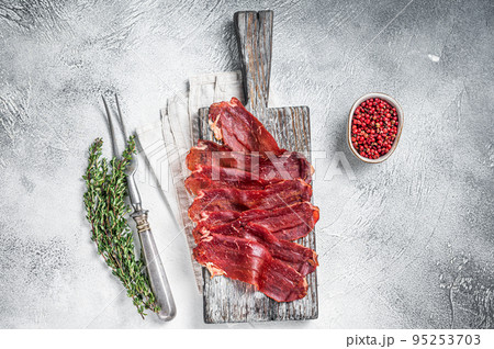 Pastirma Turkish sliced pastrami, dried beef meat with spices on wooden board. White background. Top view Pastirma Turkish sliced pastrami, dried beef meat with spices on wooden board. White background. Top view 95253703