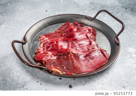 Sliced basturma, cured beef meat in steel tray. Gray background. Top view 95253773