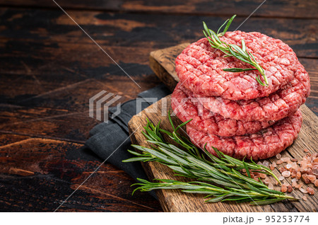 Raw minced homemade farmers grill beef burgers on chopping board with salt and rosemary. Wooden background. Top view. Copy space 95253774