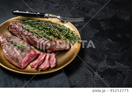 BBQ grilled Bavette Bavet beef meat steak with herbs on a plate. Black background. Top view. Copy space 95253775