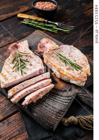 BBQ grilled pork chop steaks or cutlets sliced on wooden cutting board. Wooden background. Top view BBQ grilled pork chop steaks or cutlets sliced on wooden cutting board. Wooden background. Top view 95253884