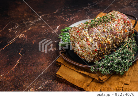 Rolled meat pork roulade with rosemary and thyme. Dark background. Top view. Copy space 95254076
