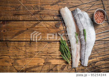 Raw fish fillets on grill with rosemary and herbs. Wooden background. Top view. Copy space Raw fish fillets on grill with rosemary and herbs. Wooden background. Top view. Copy space 95254344